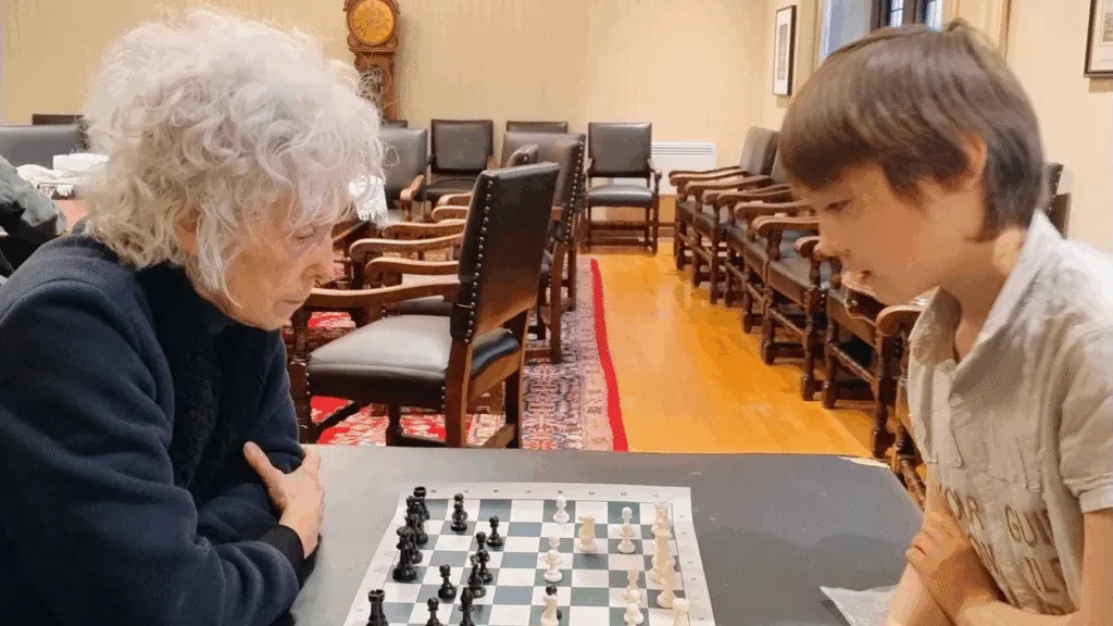 An older woman and a boy playing chess
